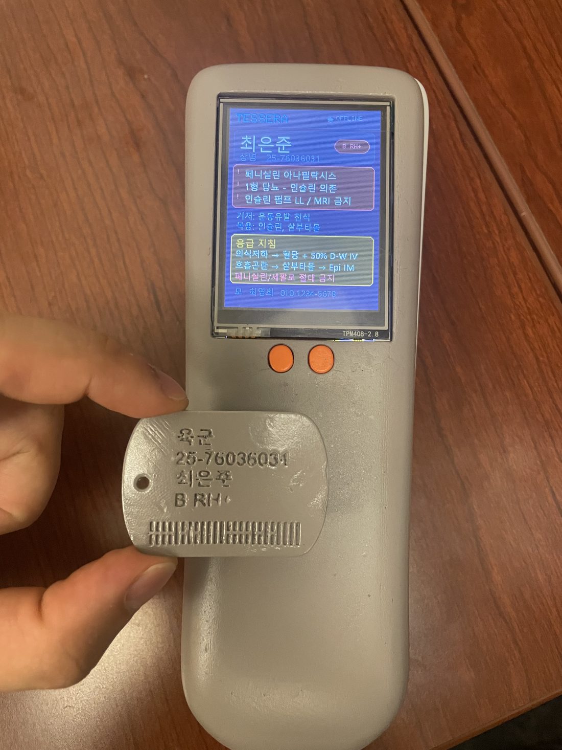 Tessera working prototype — a metal NFC dog-tag being scanned, the soldier's record shown on the handheld scanner